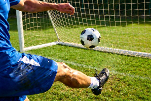 足球运动员在训练中练习射门技巧，足球飞向球门